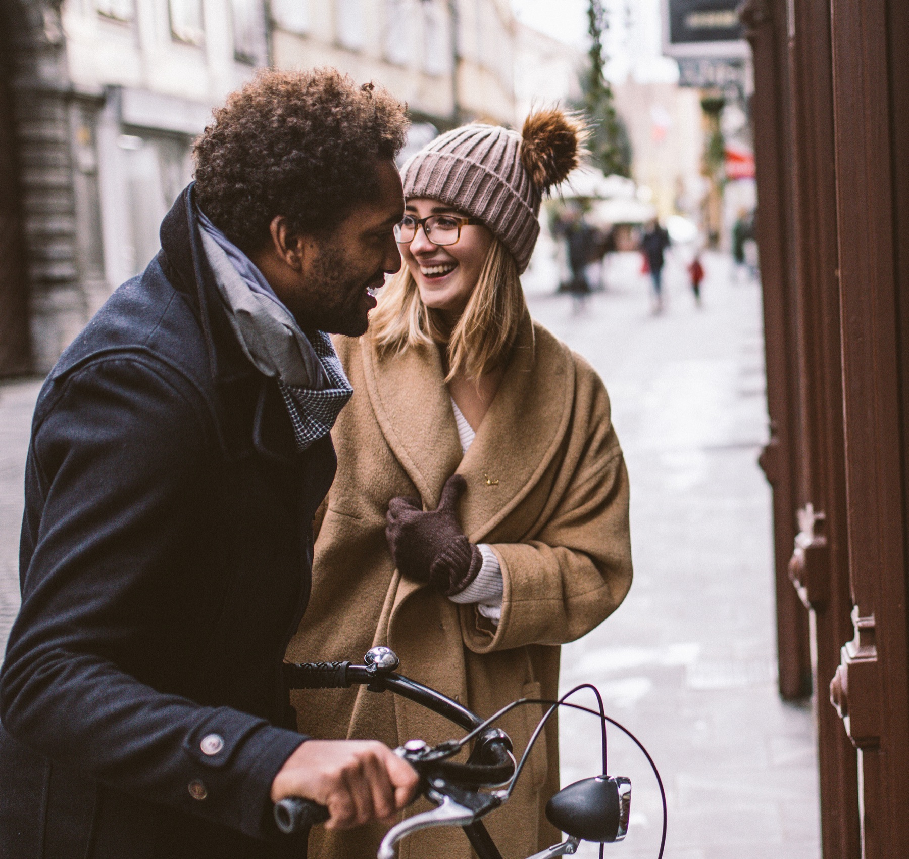 A young couple with a bicycle, laughing outside a shop window